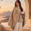 Femme portant la cape chauffante keetsoon avec une tasse de thé